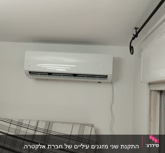 מזגן מותקן על קיר לבן עם כבל חשמל